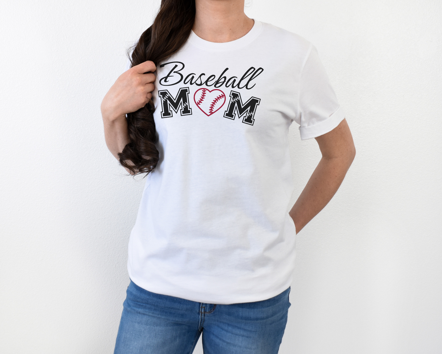 A model wearing a white t-shirt with a 'Baseball Mom' design. The design features black cursive font for "baseball" and black baseball font for "mom". A red baseball heart replaces the "O" in "mom".