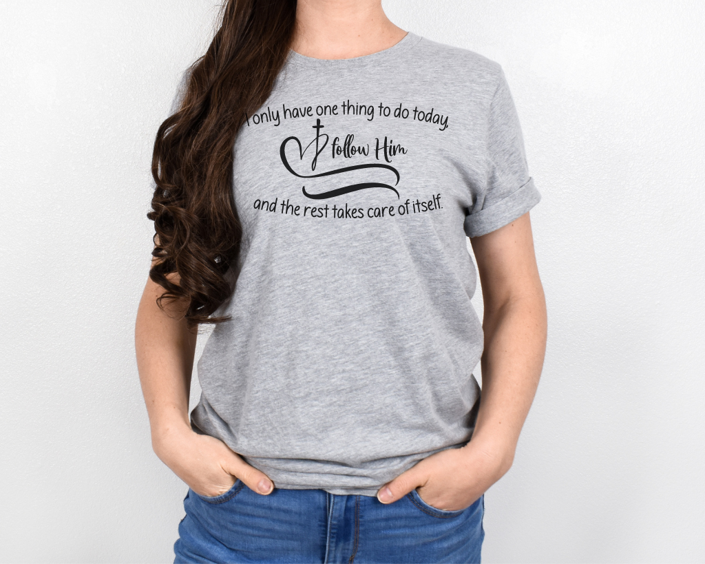 Christian light gray shirt black lettering "I only have one thing to do today, follow him, and the rest takes care of itself" with black heart & cross